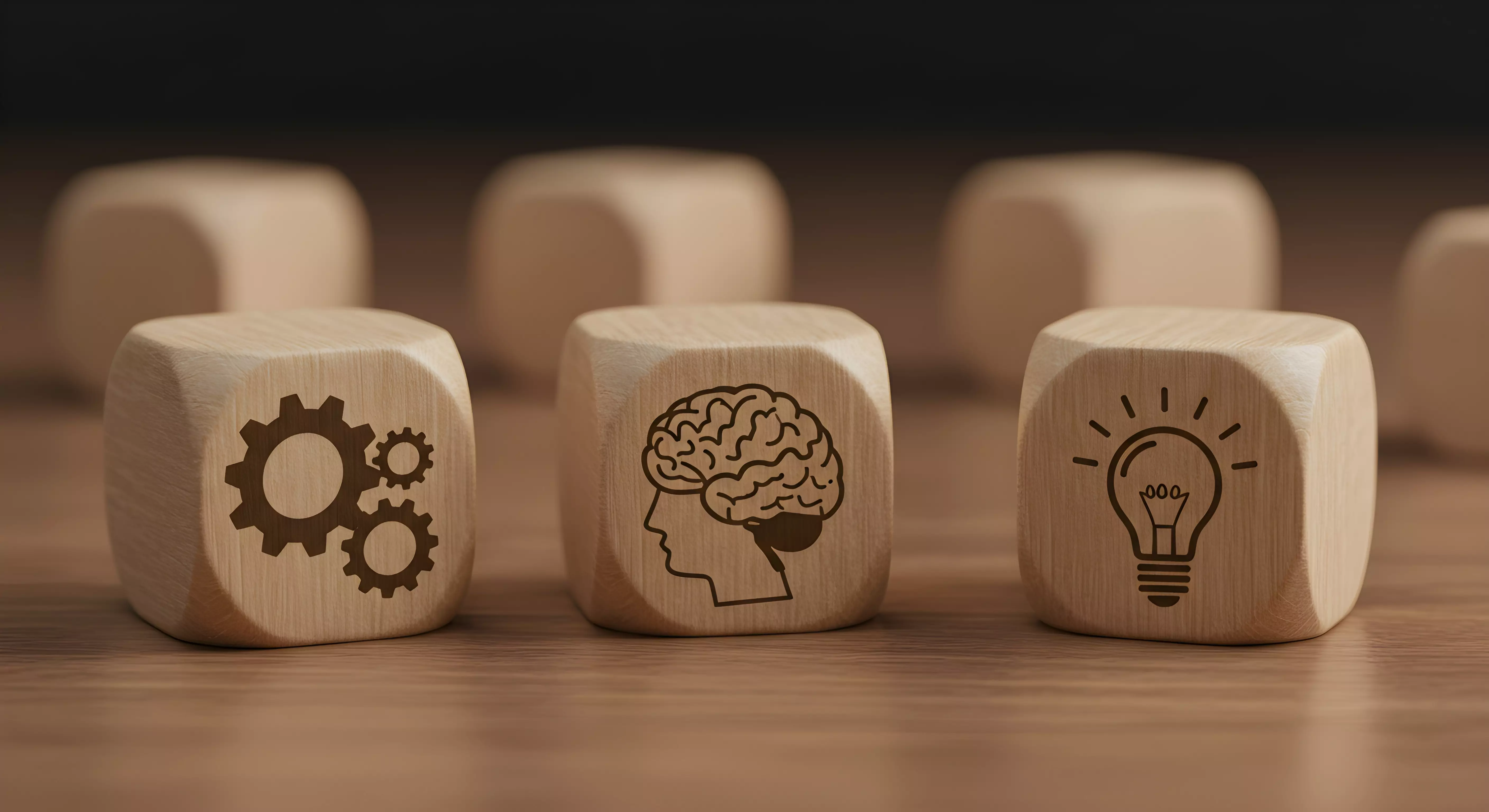 3 cubes de bois avec dessus des engrenages, un cerveau et une ampoule symblisant une idée