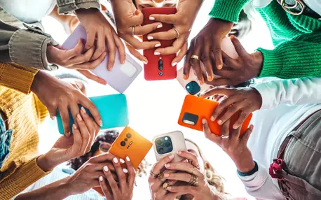 Des ados en rond vus de dessous qui sont sur leur téléphone portable